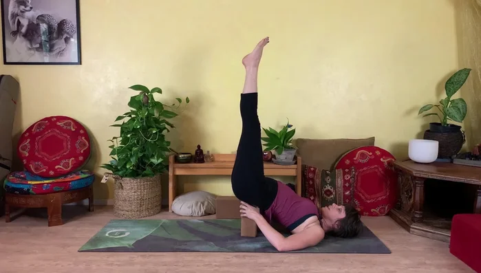 Extend your legs up toward the sky, supported by the block under your hips. This pose improves circulation.