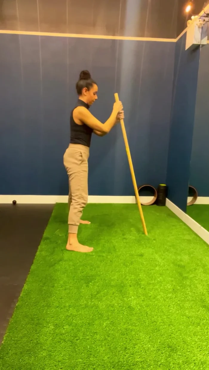 Perform a swaying motion with the rod in front of you (on a stable surface), focusing on stretching the lats and noticing sensations throughout the body.