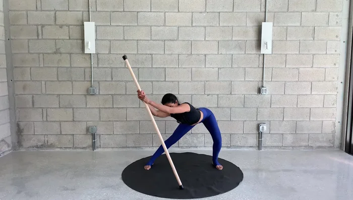 With the stick held at your side, bend knees slightly and reach up and over, then back to center.