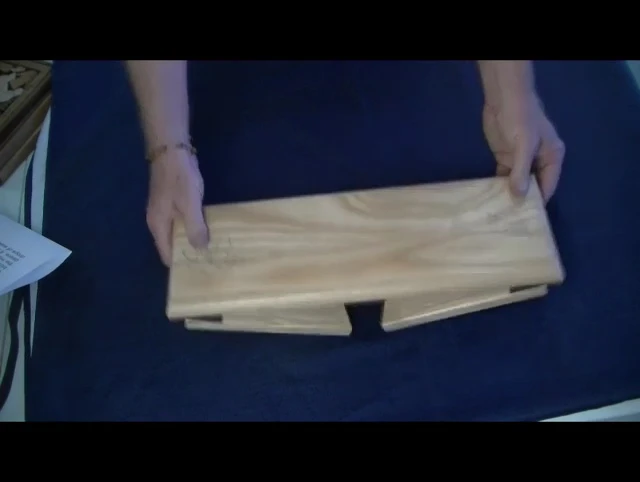 The presenter points to the thickness of the bench's wood.