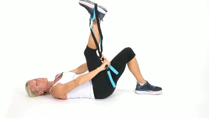 Wrap the strap around the outside of your right leg, supporting your knee. Bring your leg out to the side and then back up. Repeat.