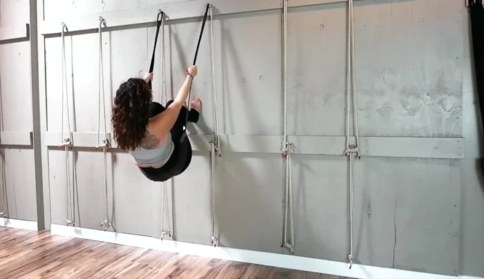 Step one foot up, then the other, bringing your knees just behind the sling.