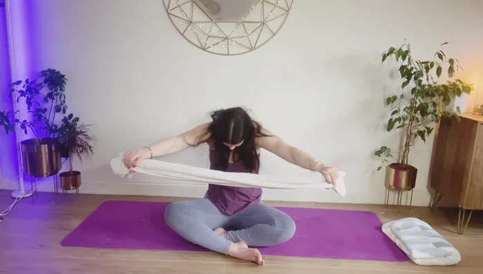 Bring the towel in front of your body and curve your spine, pulling the towel to stretch your mid-back.