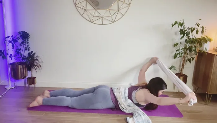 Take the smaller towel, lift it over your head, stretch your chest, and bring it back down. Repeat, stretching your shoulders back.