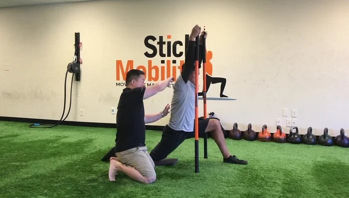 Release the glute, push the butt forward, and deepen the stretch into the hip flexor and psoas. Maintain light tension on the sticks. Hold for 6-10 seconds.