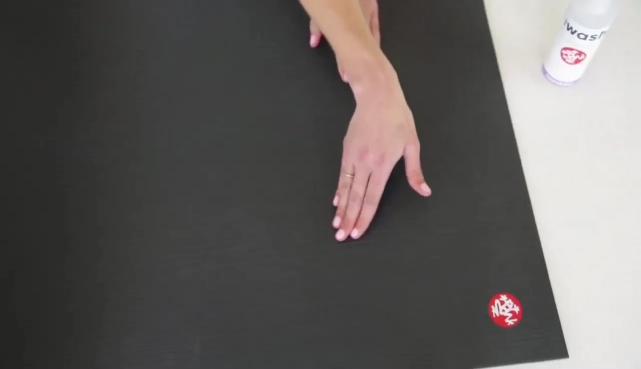 Person demonstrating cleaning the Manduka Pro mat with a specialized cleaner
