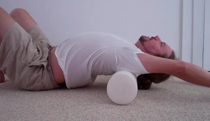 Slowly bend backward over the foam roller.