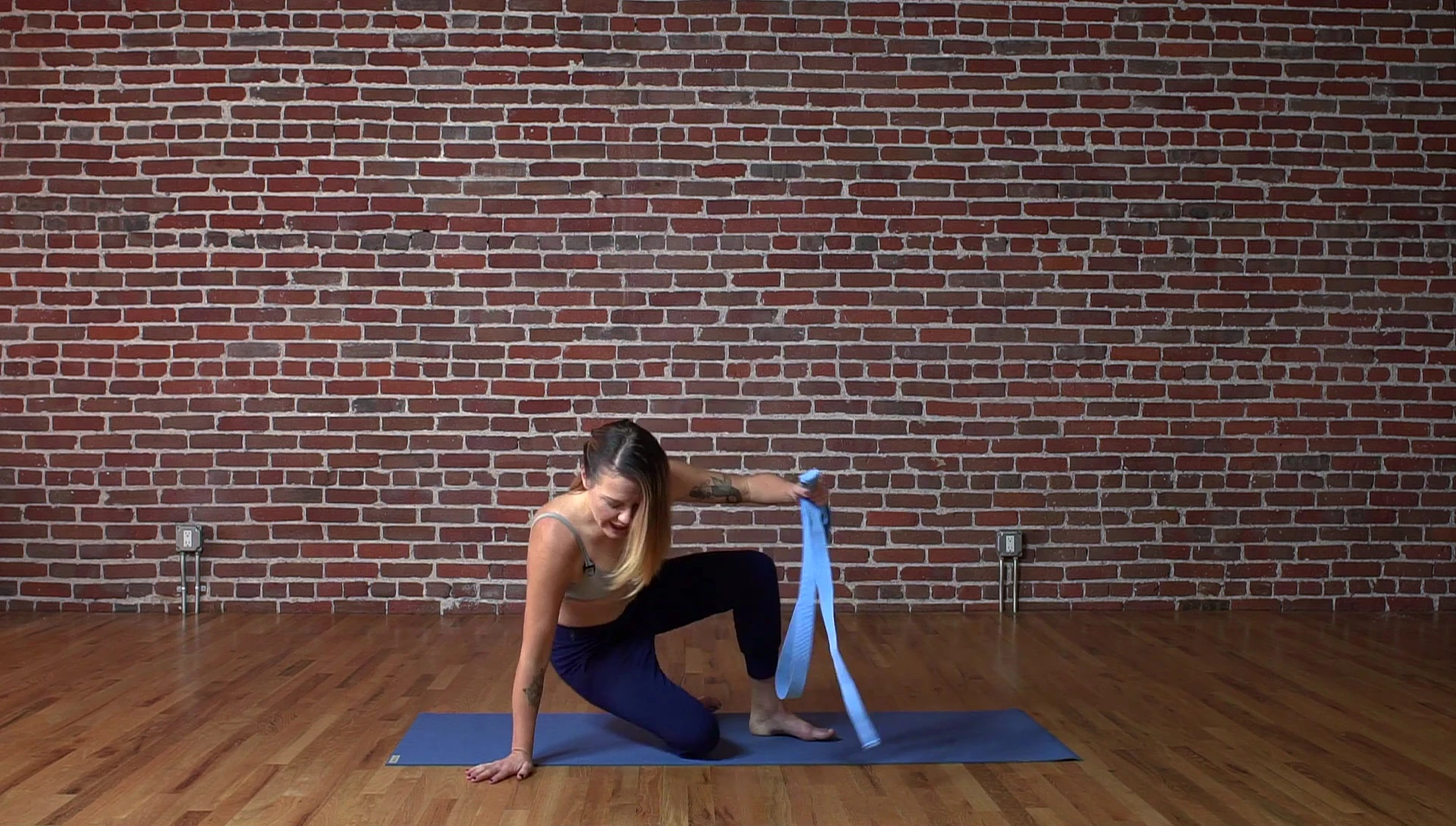 Woman sitting on yoga mat, legs extended, preparing for forward fold.