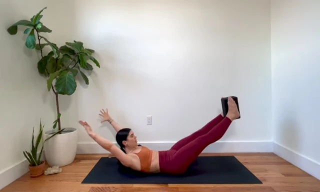 Woman performing a double leg stretch with arms extended.
