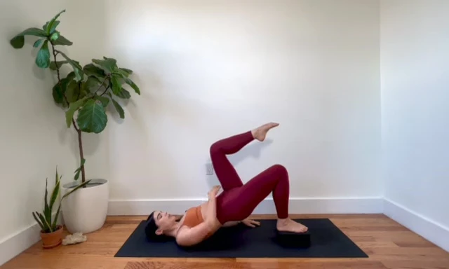 Woman performing single leg stretch with hip raised, focusing on oblique and glute activation.
