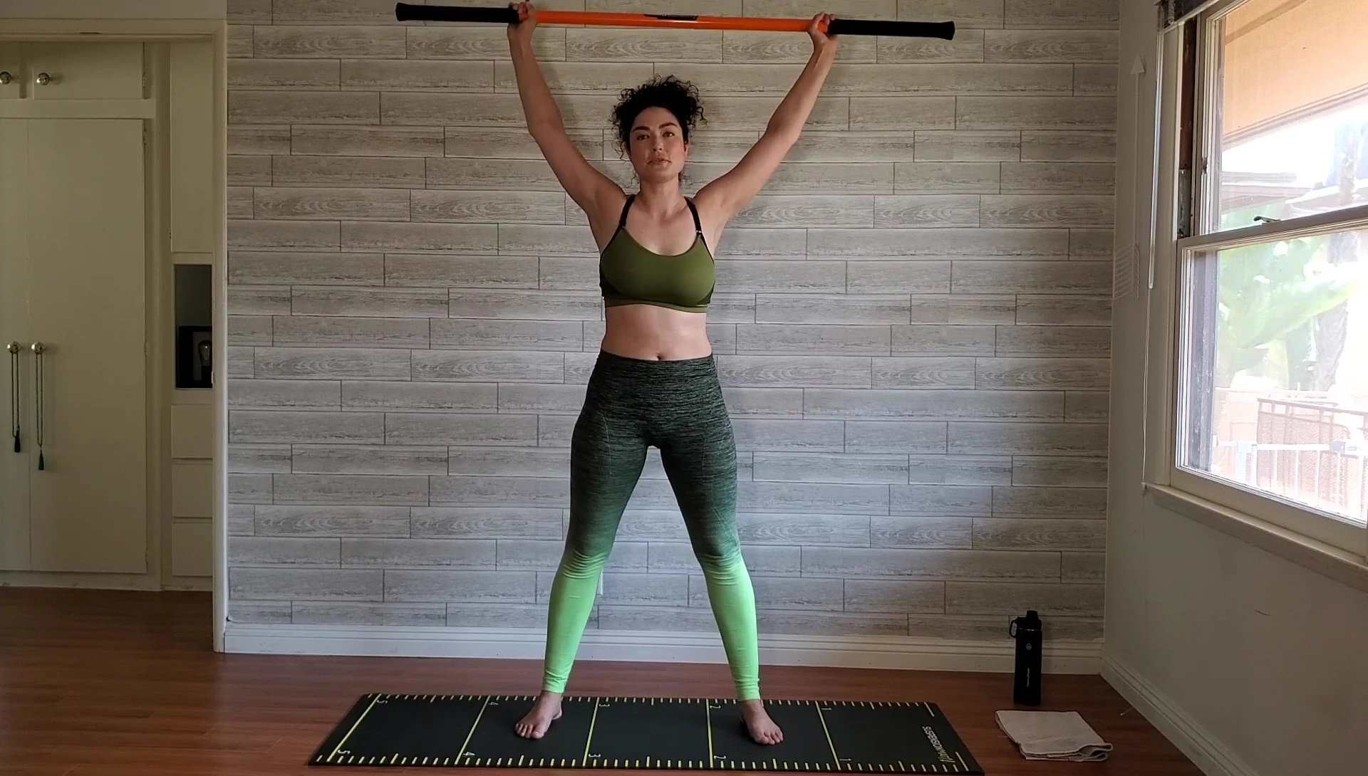 Woman performing torso twists with the stick.