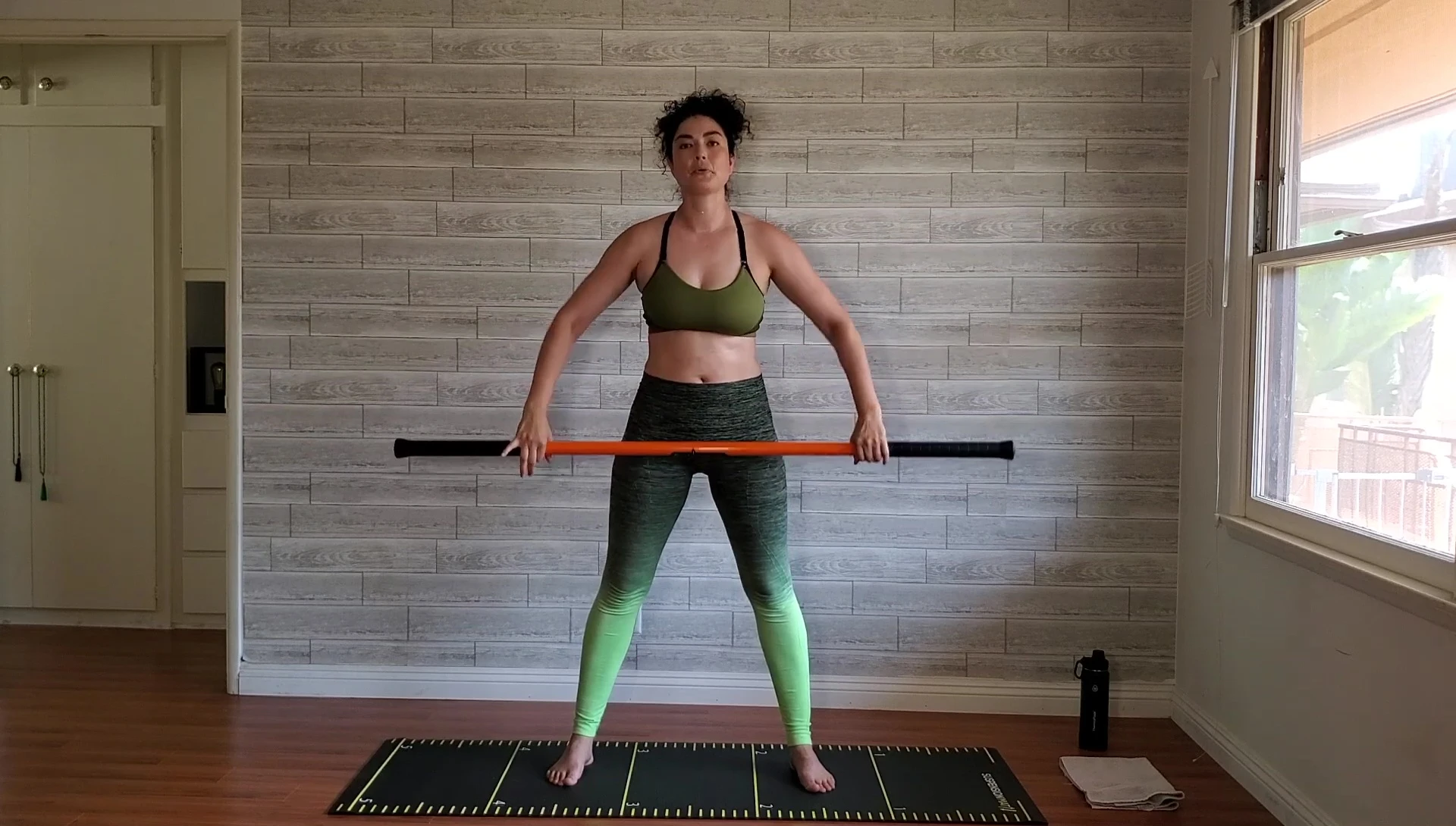 Woman demonstrating the shoulder rotation exercise with the stick.