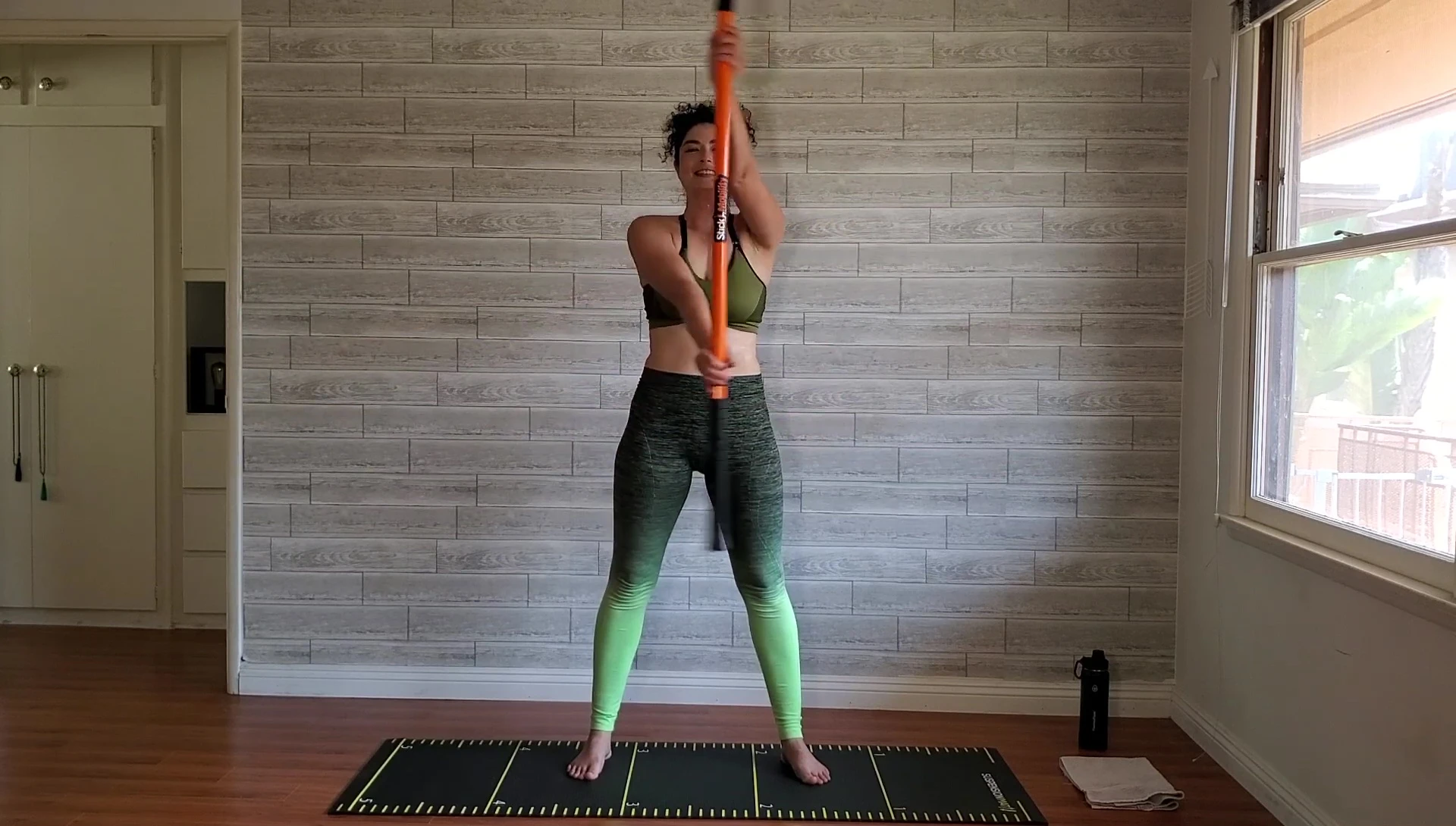 Woman performing forward fold with the stick for a deep stretch.