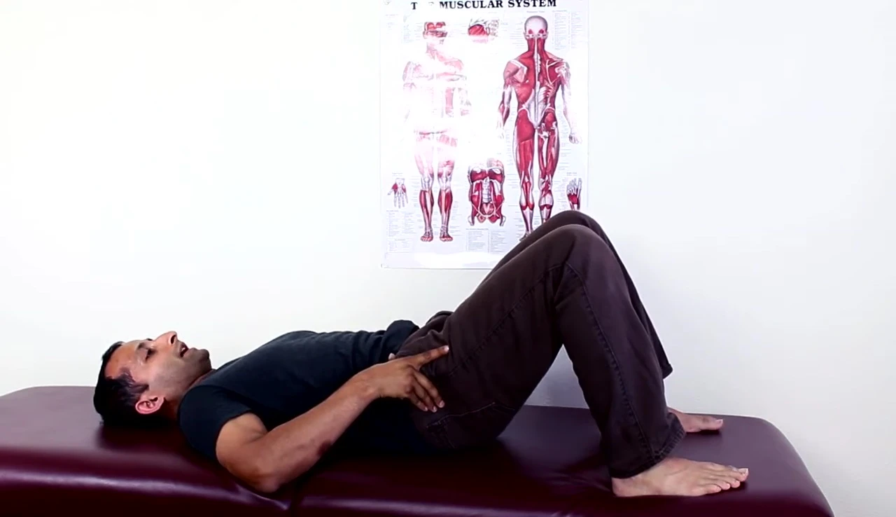Person demonstrating the controlled lowering of the pelvis onto the wedge