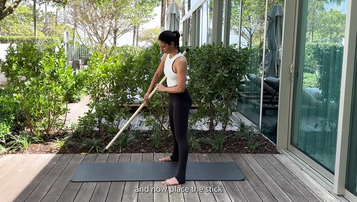 Place the stick in front of your body, arms long, body parallel to the floor, knees bent.