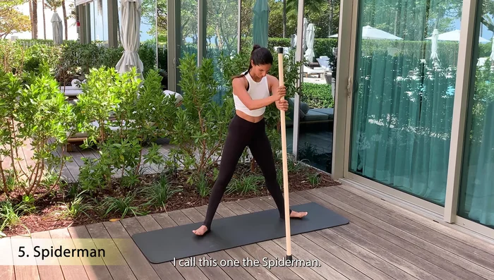 Sumo squat with stick in front for support.