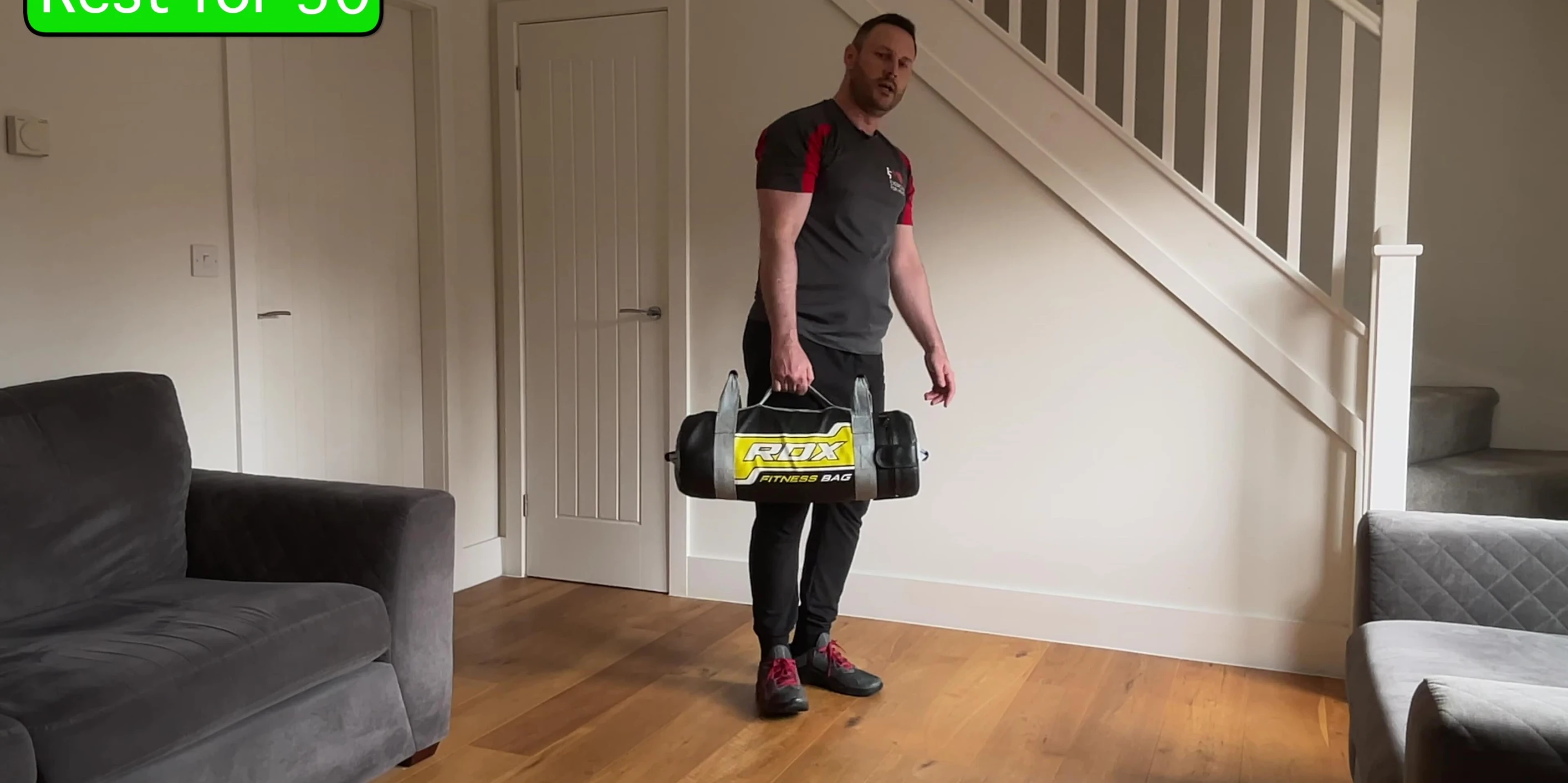 Instructor demonstrating the starting position of the side lunge with sandbag.