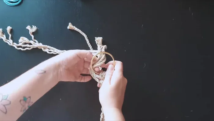 Take the left ropes and pass them through the ring and into the middle.