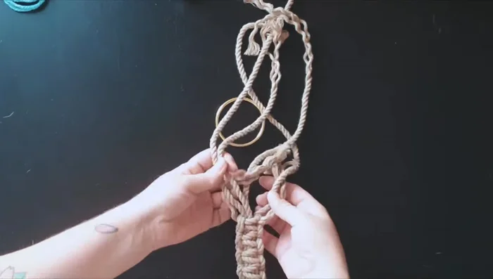 Take the left ropes and pass them through the ring and into the middle.